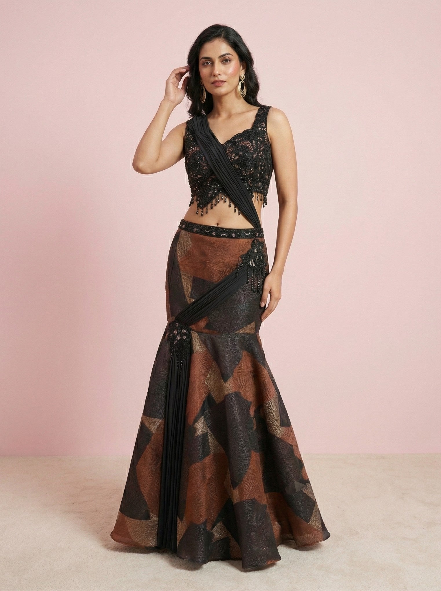 Woman wearing a black and brown drape crop top with a pink background