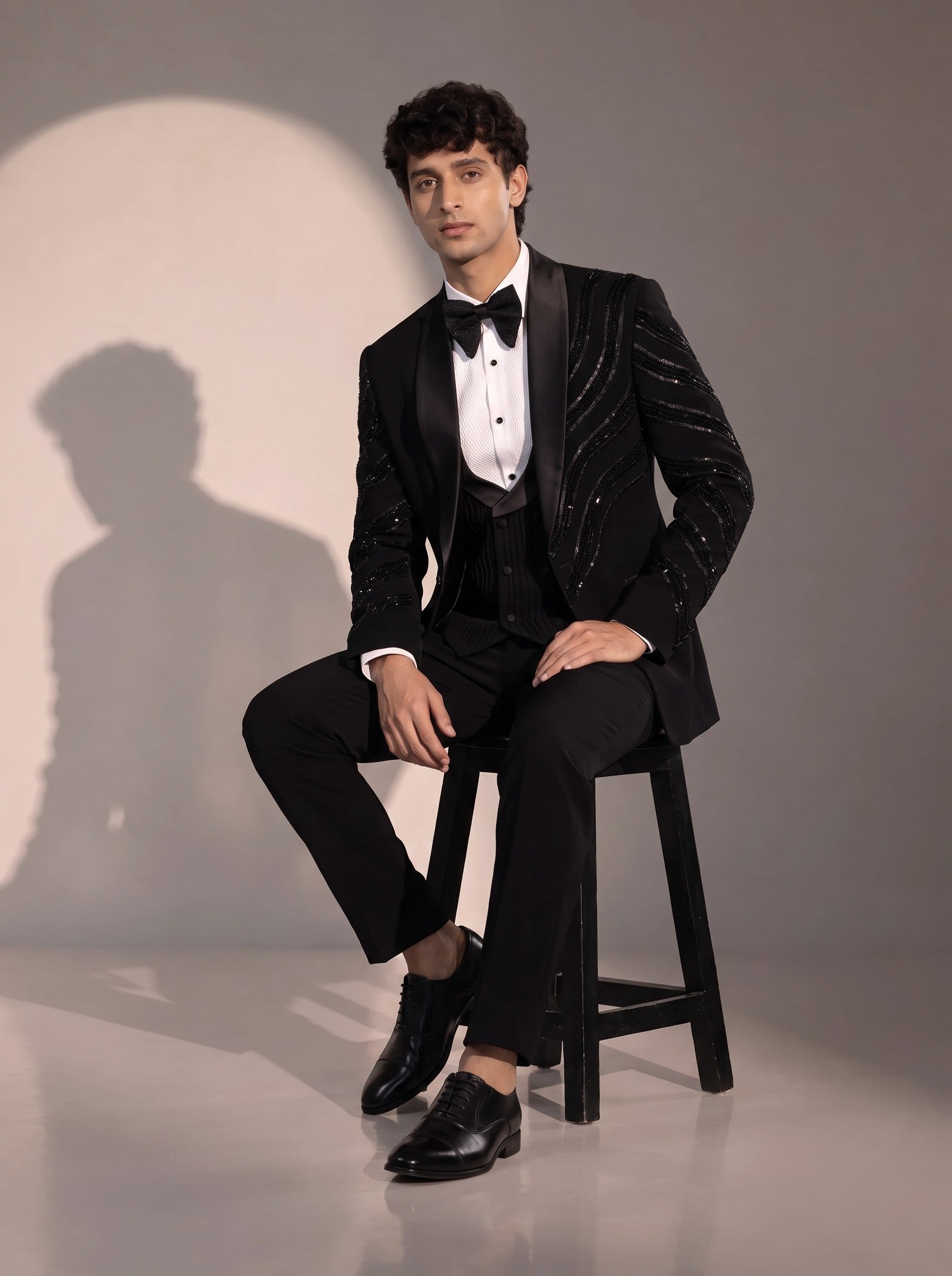 Black peak lapel beaded tuxedo suit for men - seated pose
