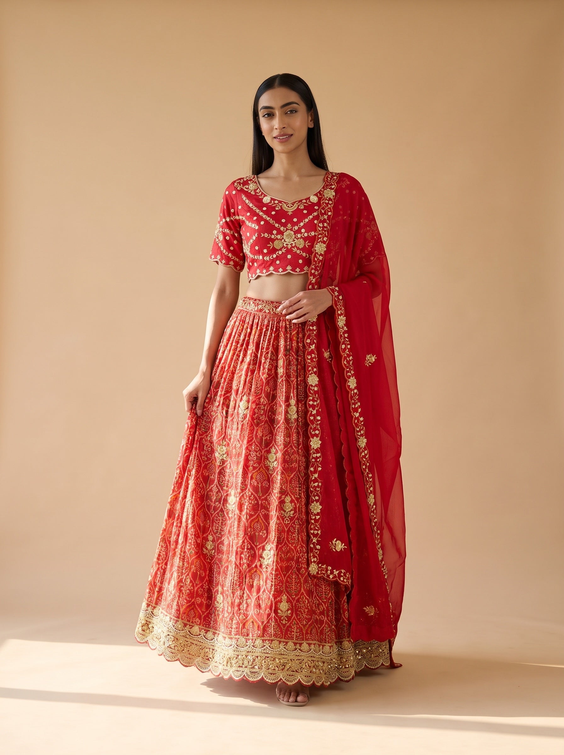 Walking view of red silk lehenga showing the flared skirt and gold embroidered hem