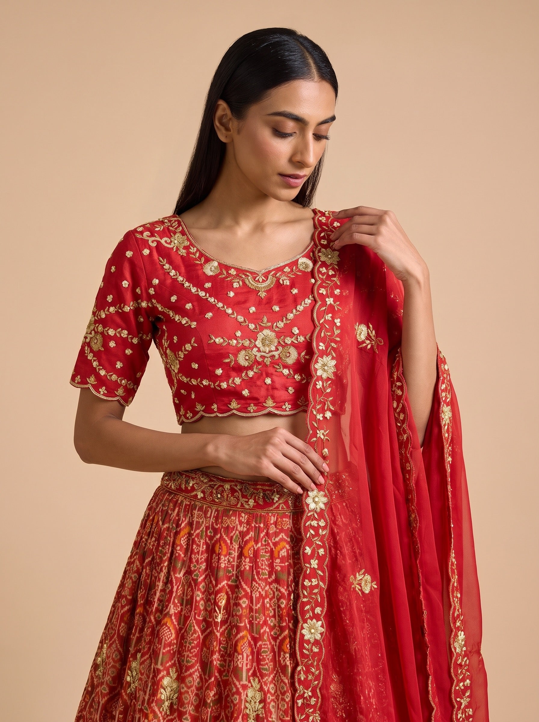 Close-up of red silk blouse with gold floral embroidery, short sleeves and matching dupatta border